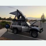 Hard-shell rooftop tent opened on an off-road vehicle at sunset