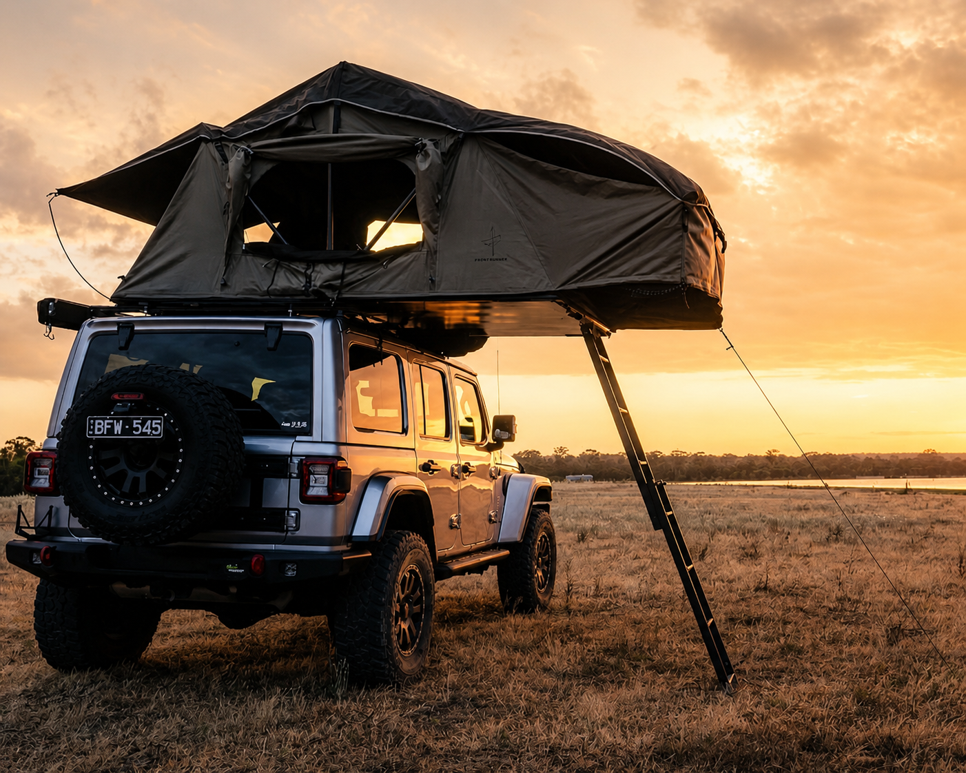 Una tenda da tetto morbida aperta su un fuoristrada al tramonto