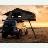 An open soft-shell rooftop tent on an off-road vehicle at sunset