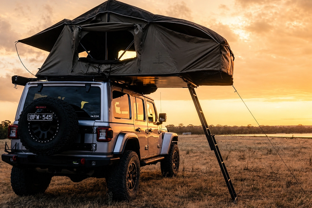 An open soft-shell rooftop tent on an off-road vehicle at sunset