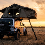 Una tenda da tetto morbida aperta su un fuoristrada al tramonto