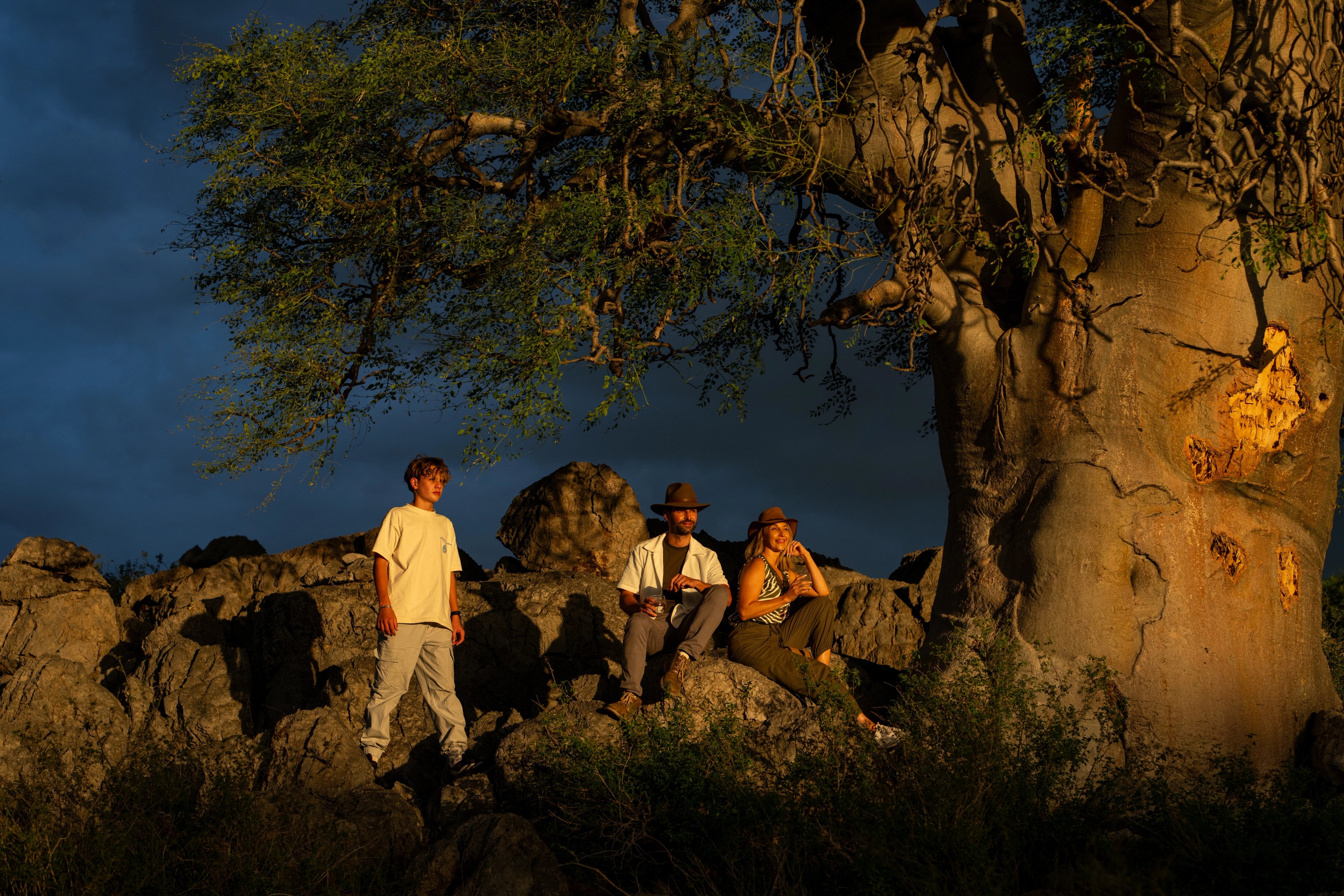 Guests pause at the Moringa tree to admire the sunset, taking in not only the breathtaking sky but also the unique elephant markings etched into its trunk. 