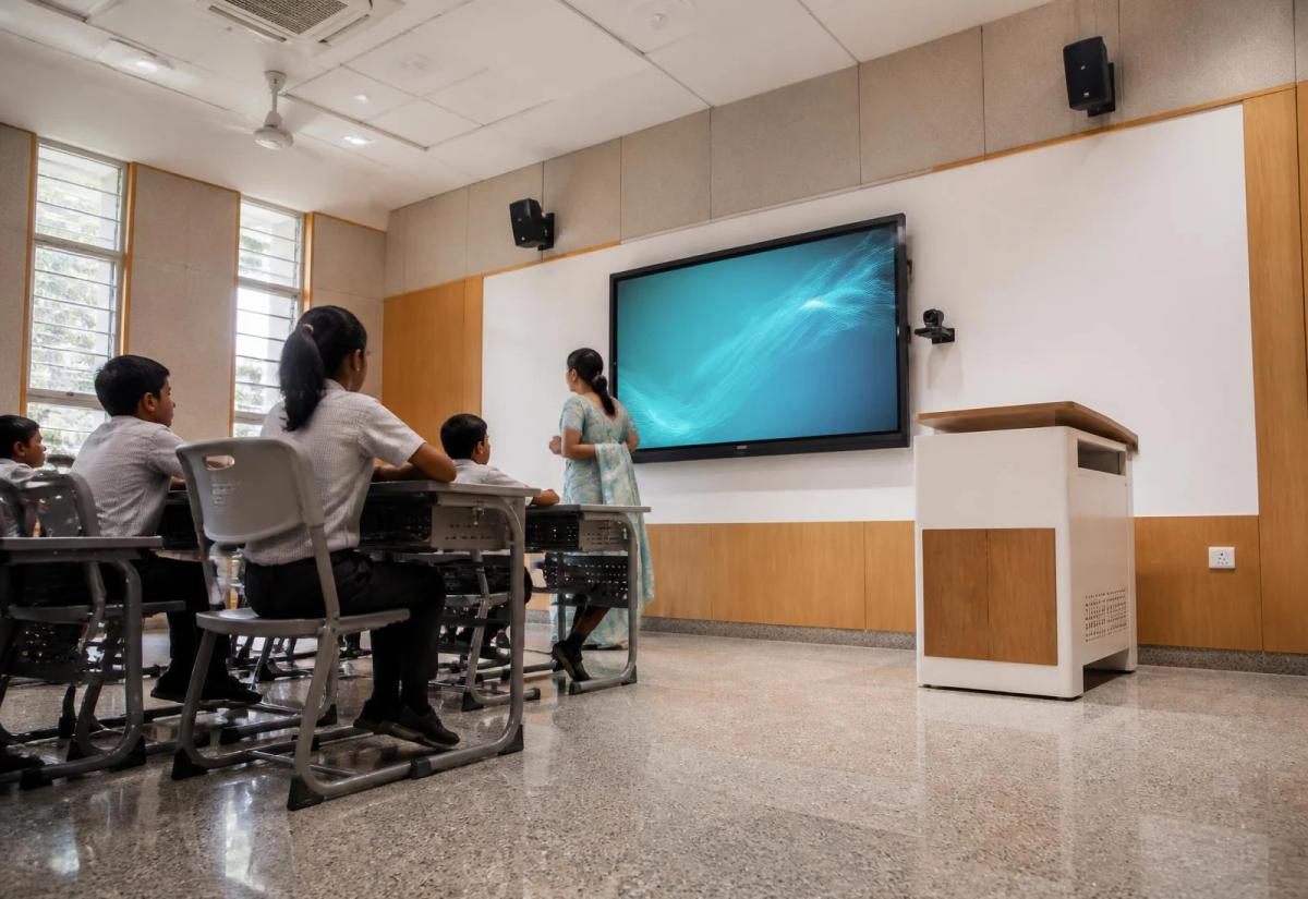 Teacher presenting to students in a classroom with an interactive display