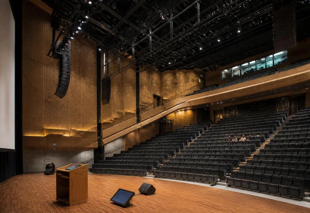 Auditorium with stage, lectern, projection screen, and professional audio