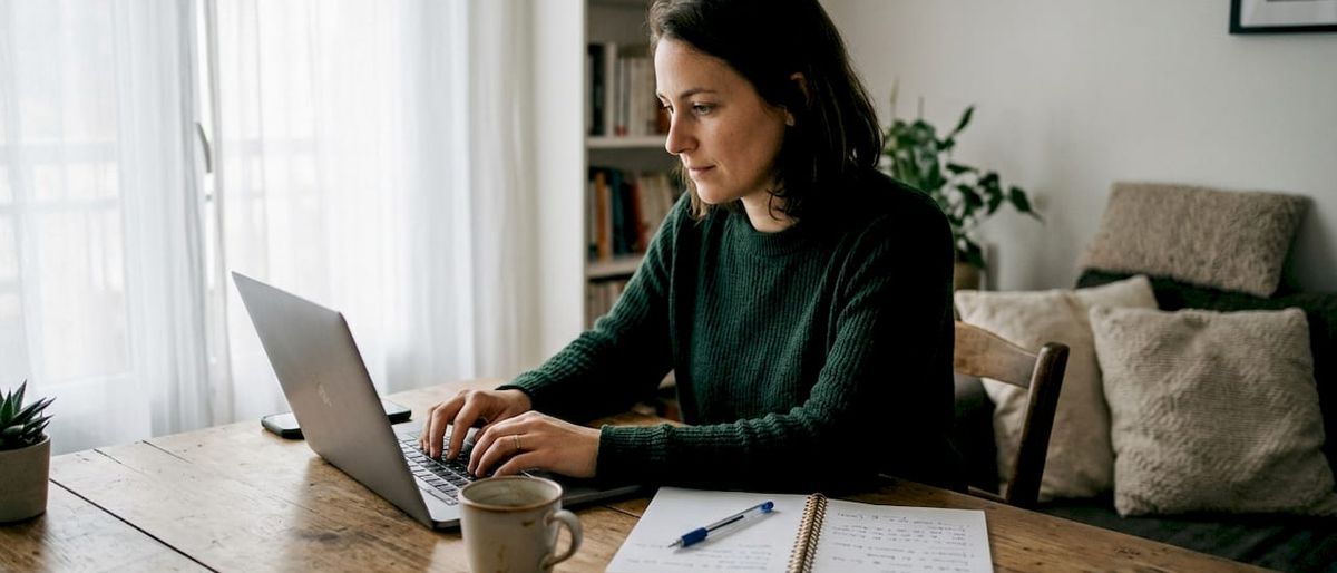 Une femme rédige sa lettre de motivation devant son ordinateur au bureau.