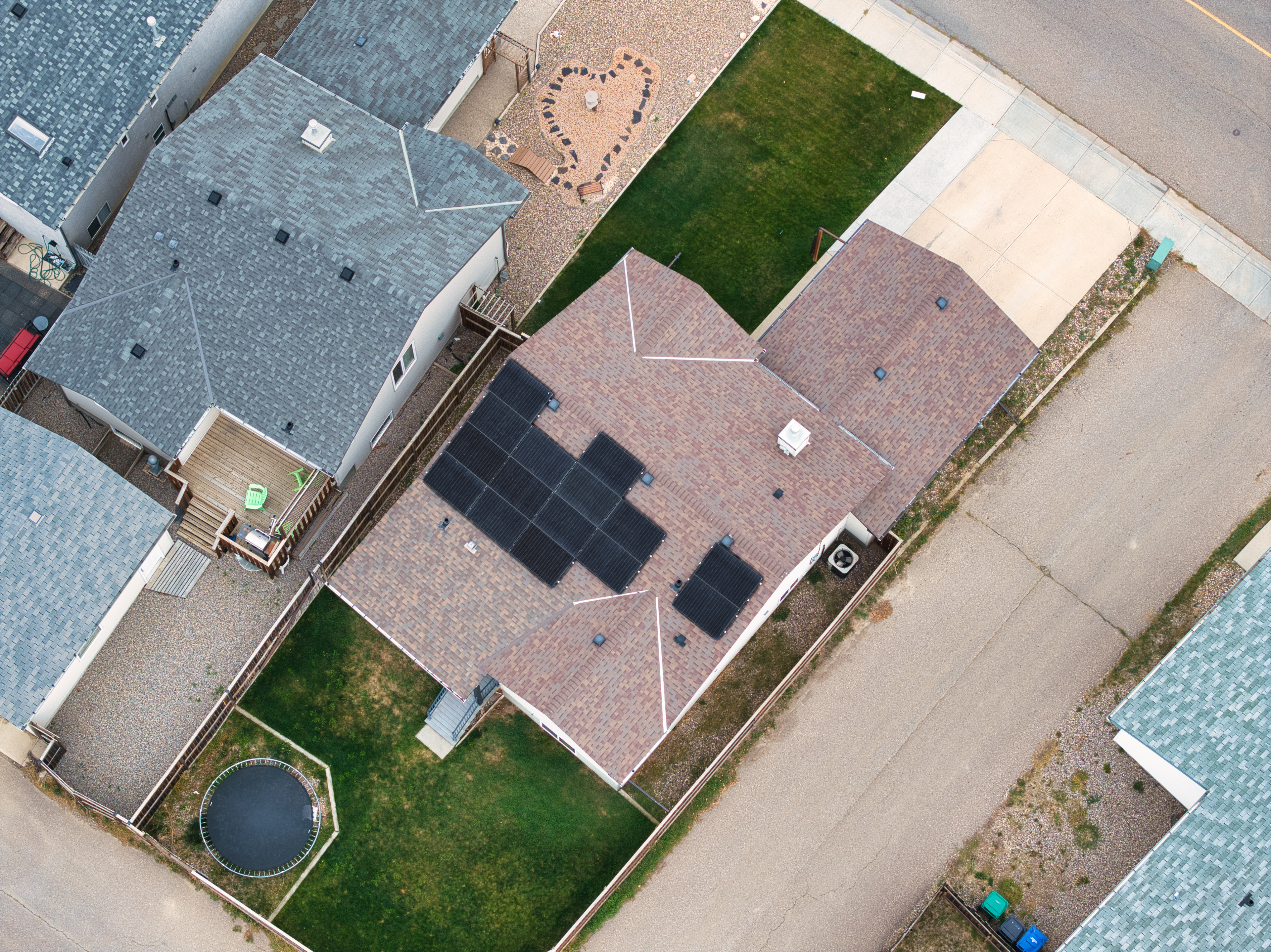 Top-down aerial view of a professional residential solar panel installation by Firefly Solar on a brown shingled roof, featuring an optimized black solar array layout on an Alberta property.