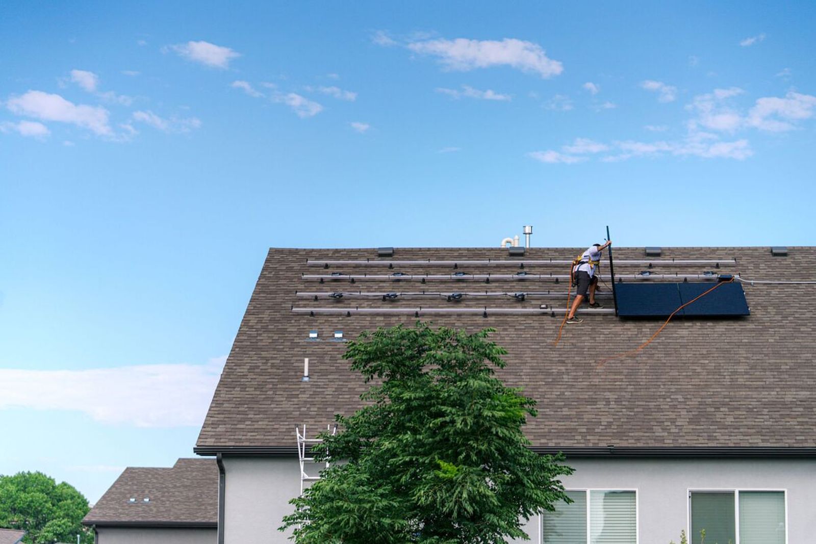 Installer mounting solar panel racking on new home rooftop