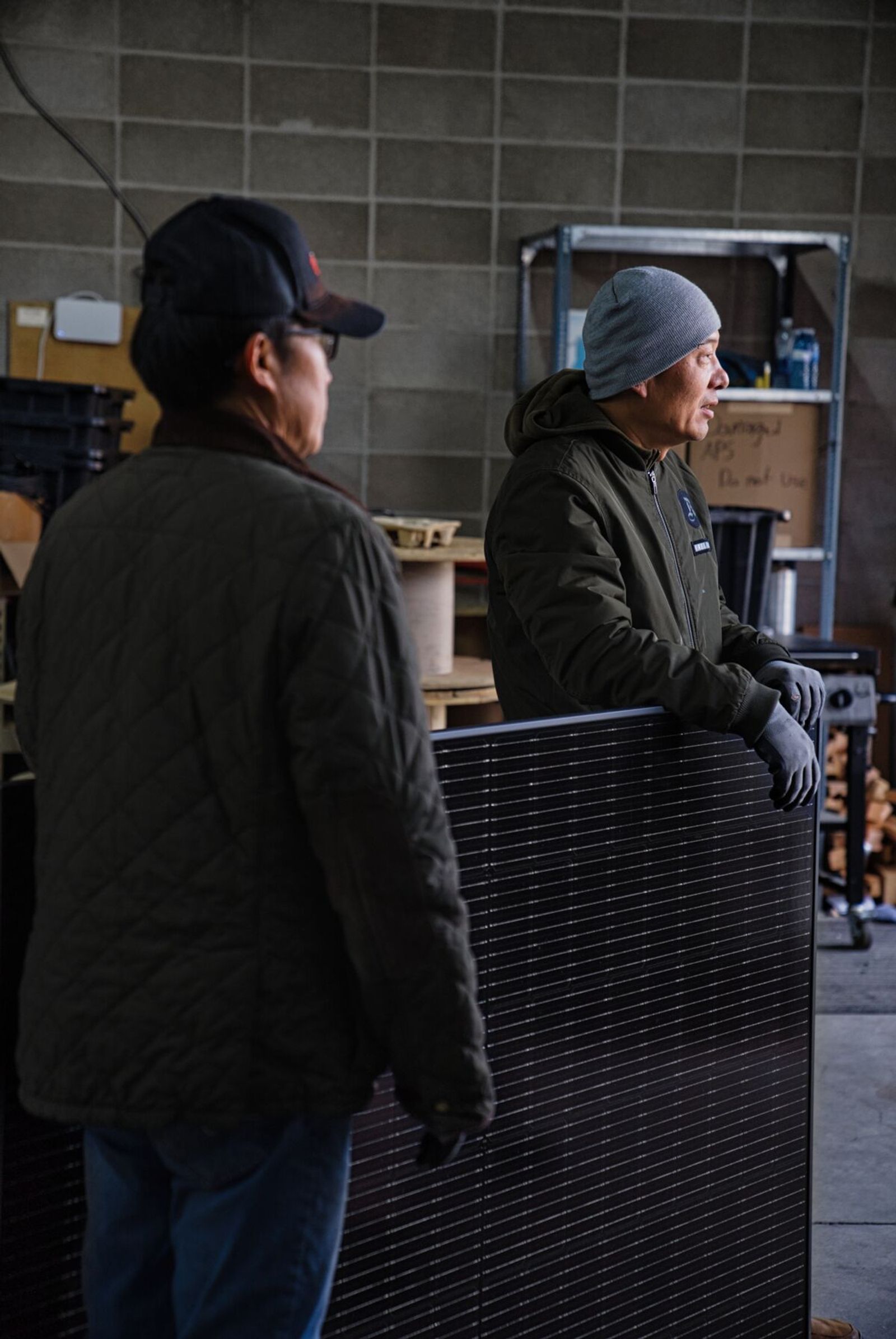 Firefly Solar engineers handling commercial solar panel in warehouse