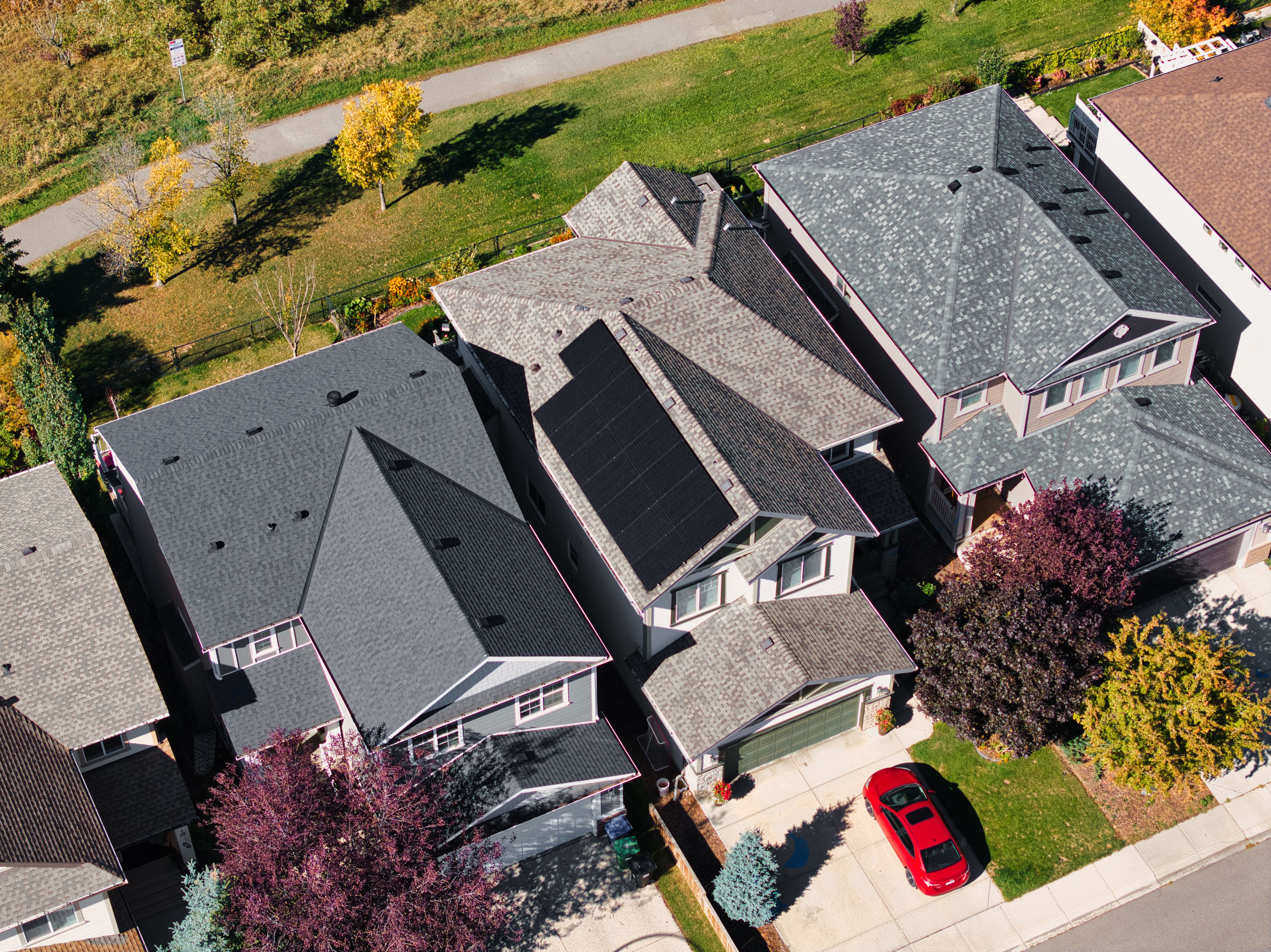 Aerial view of a custom residential solar panel array installed by Firefly Solar on a steep grey shingled roof, showcasing clean energy production in an Alberta neighborhood.