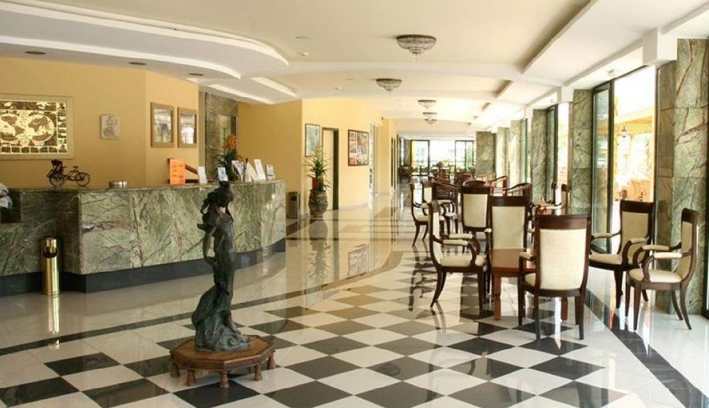 Recepție elegantă, cu podea în carouri alb-negru, sculptură centrală și mese cu scaune confortabile.