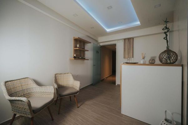 Recepție modernă, cu două scaune din ratan, mese decorative și iluminare ambientală, într-un spa.