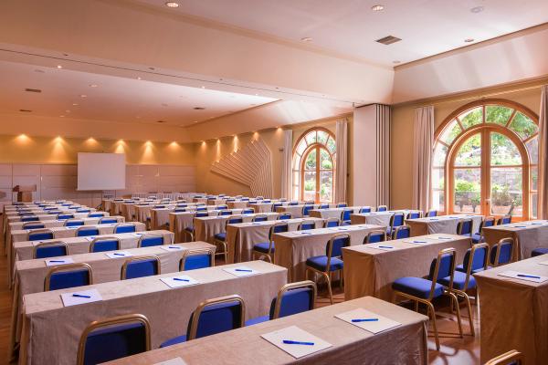 Săli de conferințe cu mese aranjate, scaune albastre și feronerie luminoasă, cu feronerie de sticlă.