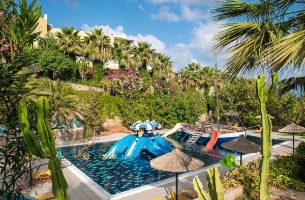 Complex turistic cu piscină, tobogane și plante tropicale, sub un cer senin. Atmosferă de relaxare și distracție.