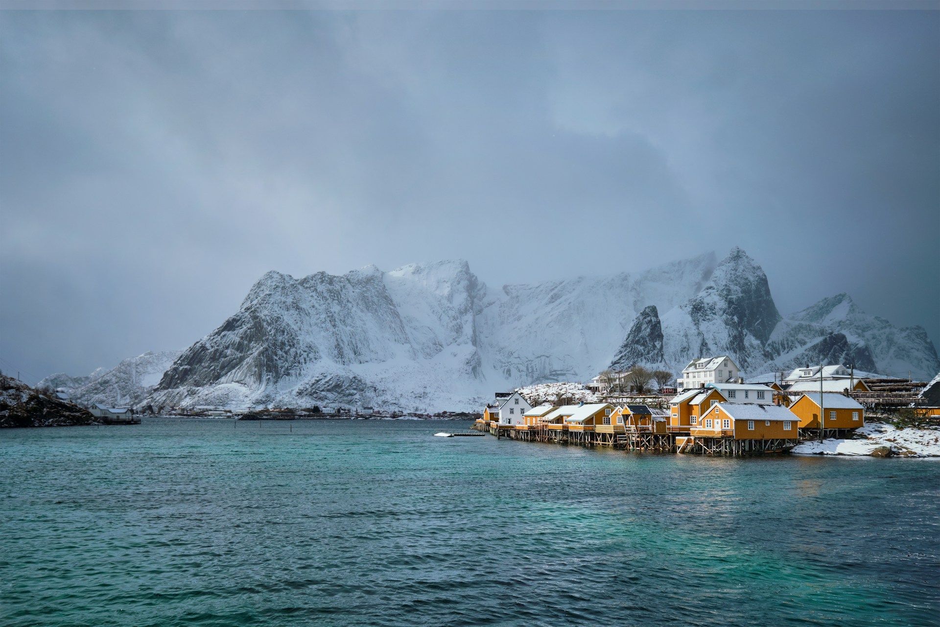 Fishermen's cabins by the water under snowy peaks in the Lofoten Islands