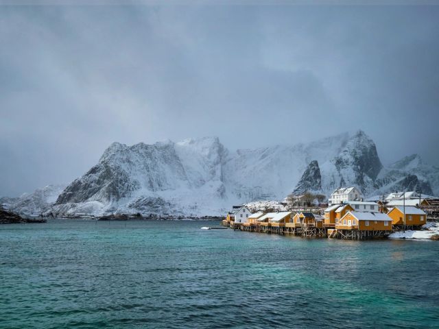 Fishermen's cabins by the water under snowy peaks in the Lofoten Islands