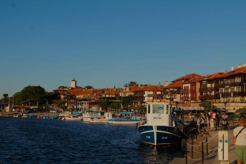 Portul din Orașul Vechi Nessebar, Bulgaria, cu bărci și clădiri tradiționale la apus.
