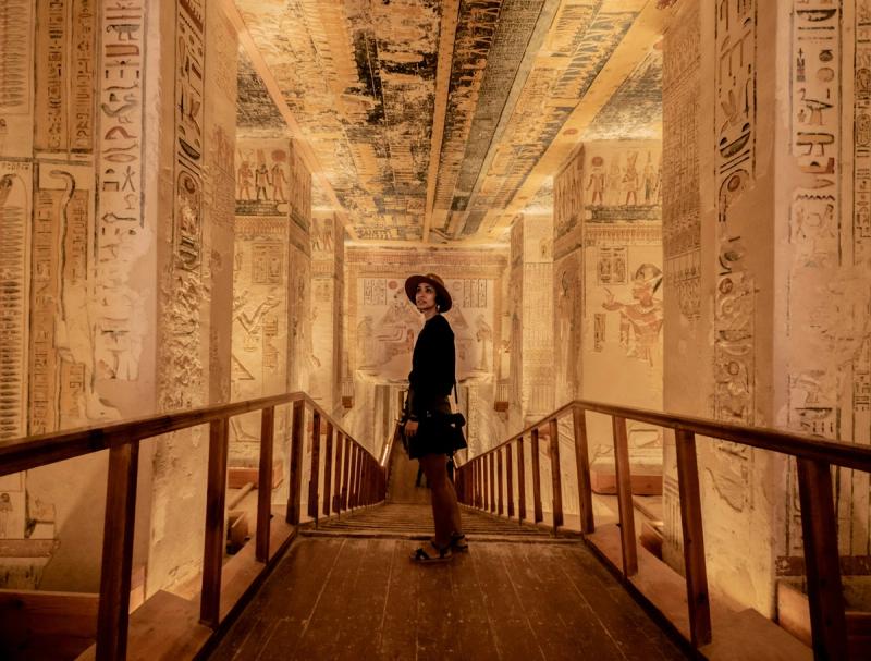 Turistă într-un coridor decorat cu hieroglife în templul din Luxor, Egipt, iluminat cald.