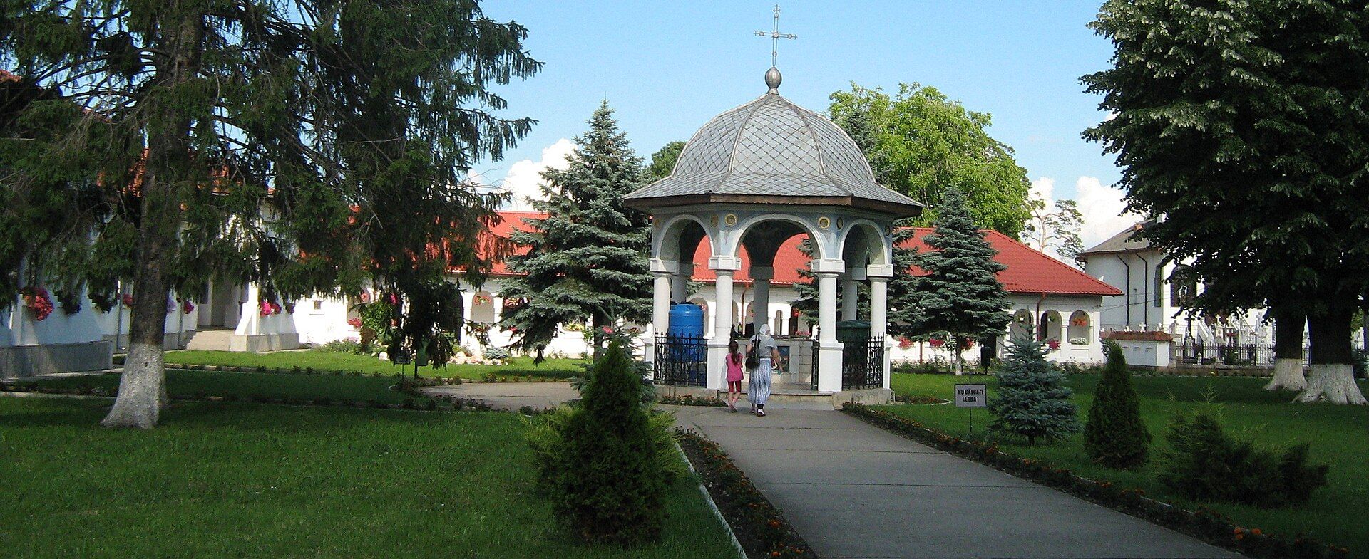A flower-lined path and gazebo at Ghighiu Monastery