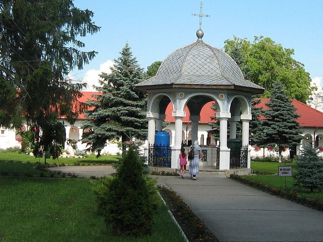 A flower-lined path and gazebo at Ghighiu Monastery