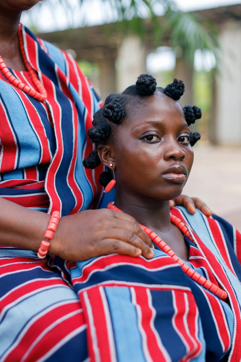 Femeie din Lagos, Nigeria, purtând haine tradiționale colorate și podoabe din mărgele roșii.