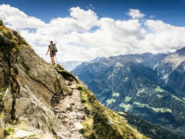 A hiker on a mountain path in the Italian Alps