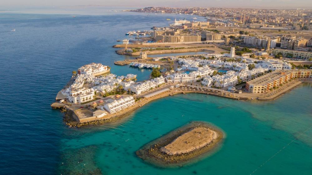 Vedere aeriană a stațiunii Hurghada, Egipt, cu clădiri albe și apă turcoaz a Mării Roșii.