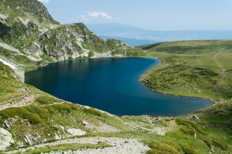 Lacul Rila din Munții Rila, Bulgaria, înconjurat de versanți verzi și poteci montane.