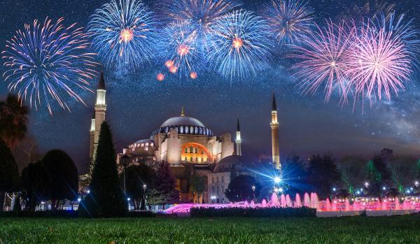 Focuri de artificii de Revelion deasupra Hagiei Sofia din Istanbul, cu fântâni iluminate în prim-plan.