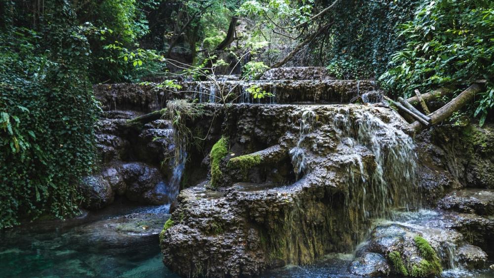 Cascade terasate la Krushuna, Bulgaria, cu apă limpede și stânci acoperite de mușchi.