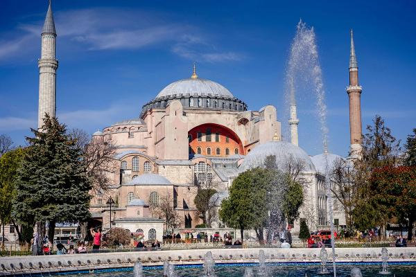 Hagia Sofia din Istanbul într-o zi senină, cu fântâni și turiști în prim-plan.