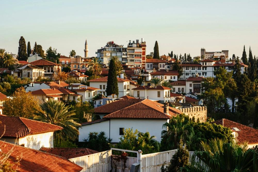 Vedere panoramică asupra orașului vechi Kaleiçi din Antalya, Turcia, cu acoperișuri roșii tradiționale, palmieri și clădiri istorice. Imaginea surprinde farmecul mediteranean al cartierului vechi, un loc plin de istorie și atmosferă autentică.