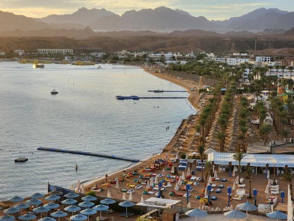Stațiune pe plajă în Sharm El Sheikh cu palmieri și munții Sinai în fundal, Egipt.
