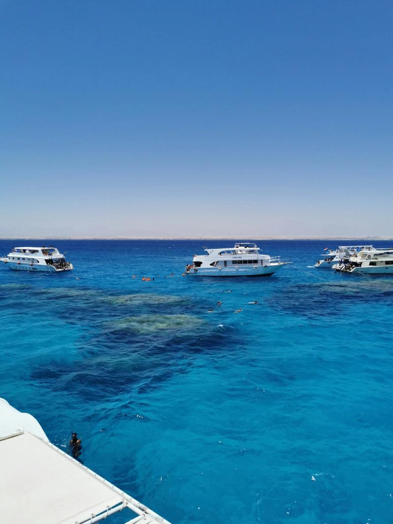 Bărci de snorkelling pe apele turcoaz ale Mării Roșii în Hurghada, Egipt, cu recif vizibil.