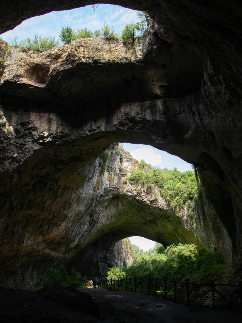 Peștera Devetashka din Bulgaria, cu bolți uriașe de piatră și lumină naturală ce pătrunde prin deschideri.