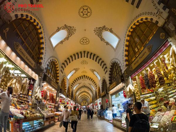 Interiorul Marelui Bazar din Istanbul, cu magazine pline de produse tradiționale și turiști care explorează.