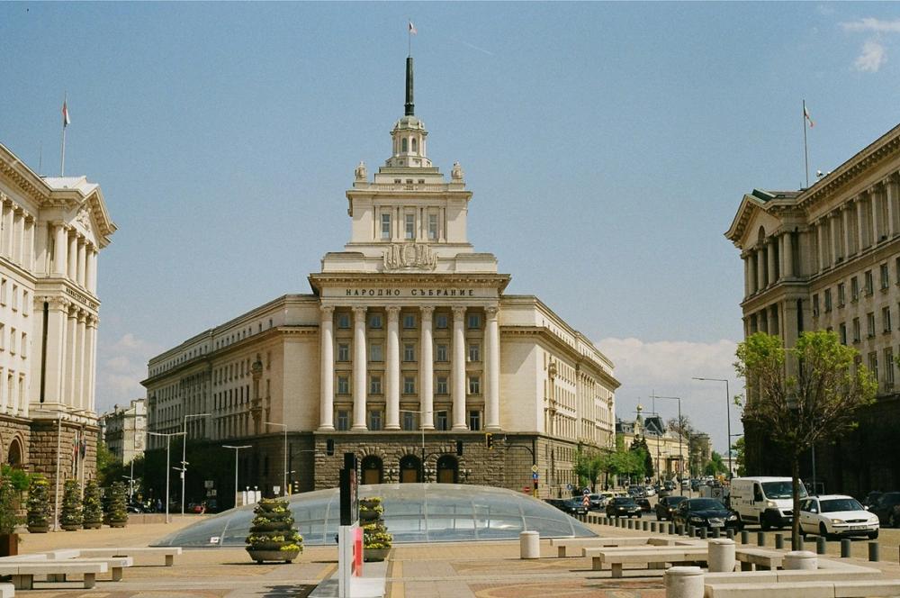 Clădirea Adunării Naționale a Bulgariei de pe Bulevardul Knyaz Alexander Dondukov din Sofia se impune prin arhitectura sa monumentală, cu coloane impunătoare și o fațadă simetrică. Spațiul urban din jur este bine organizat, iar atmosfera transmite eleganța instituțională a centrului administrativ al capitalei bulgare.