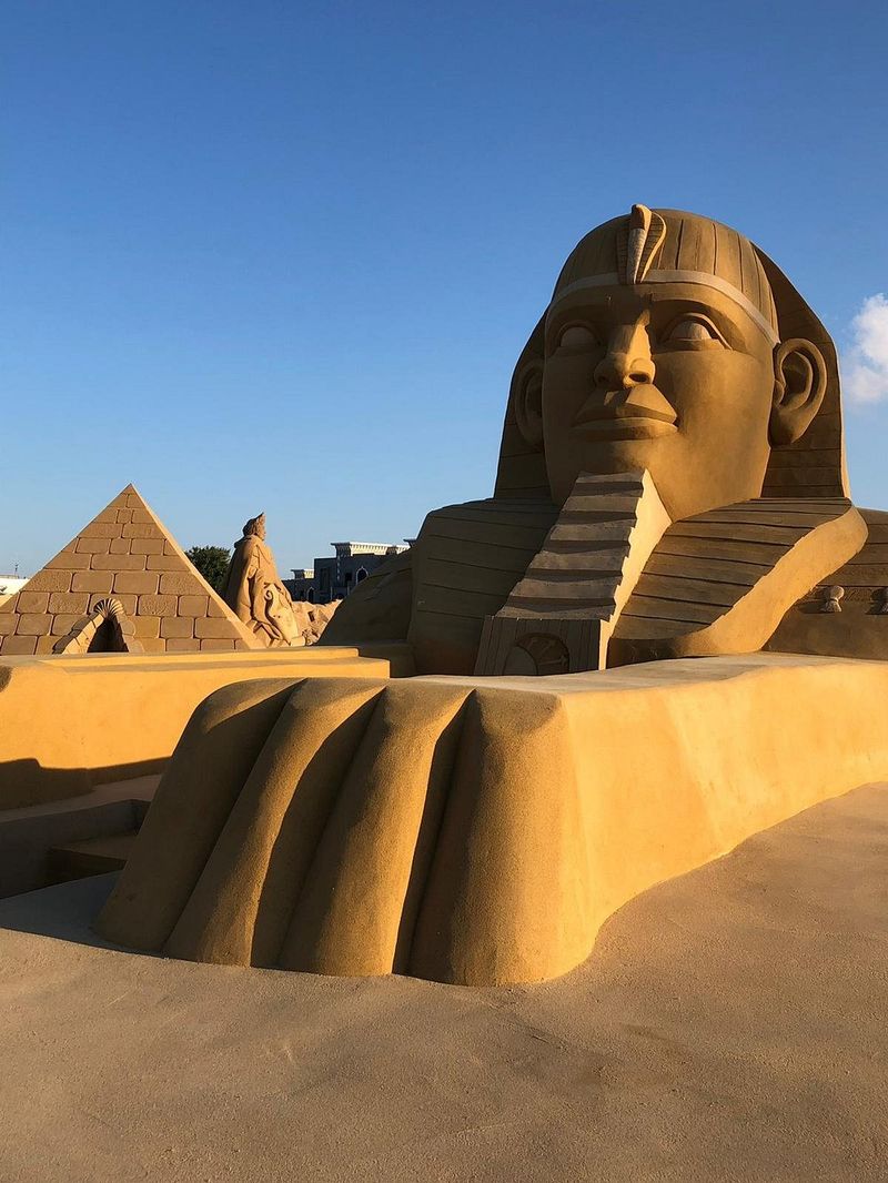 Statuie de nisip cu faraon și piramide la Sand City Hurghada, Egipt, sub cer senin.