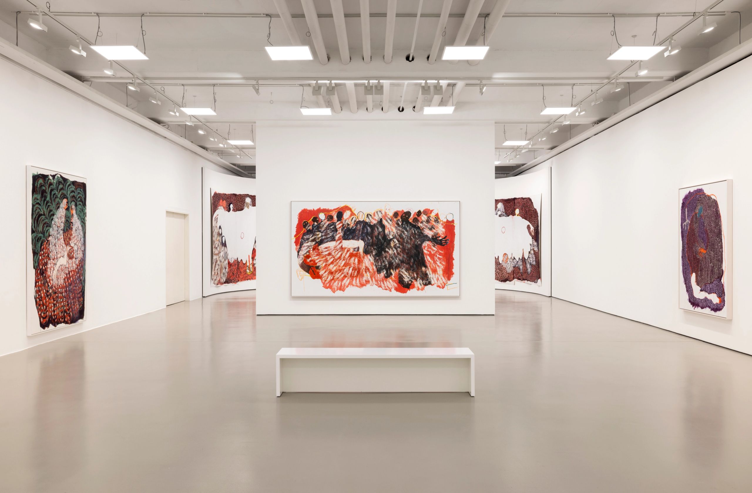 A modern art gallery with abstract paintings on white walls and a white bench.