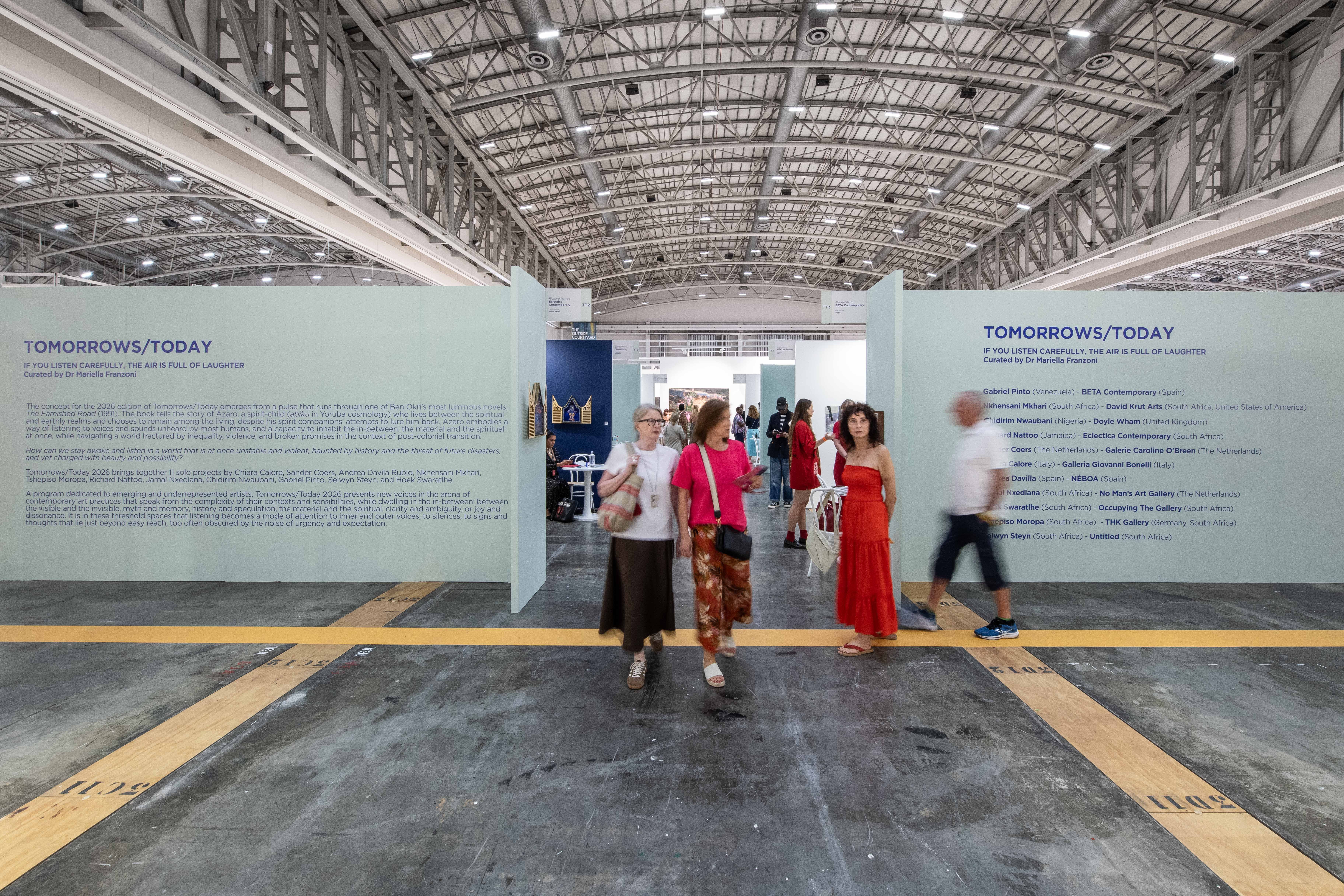 People walk through a large exhibition hall with prominent signs for the "TOMORROWS/TODAY" exhibit.