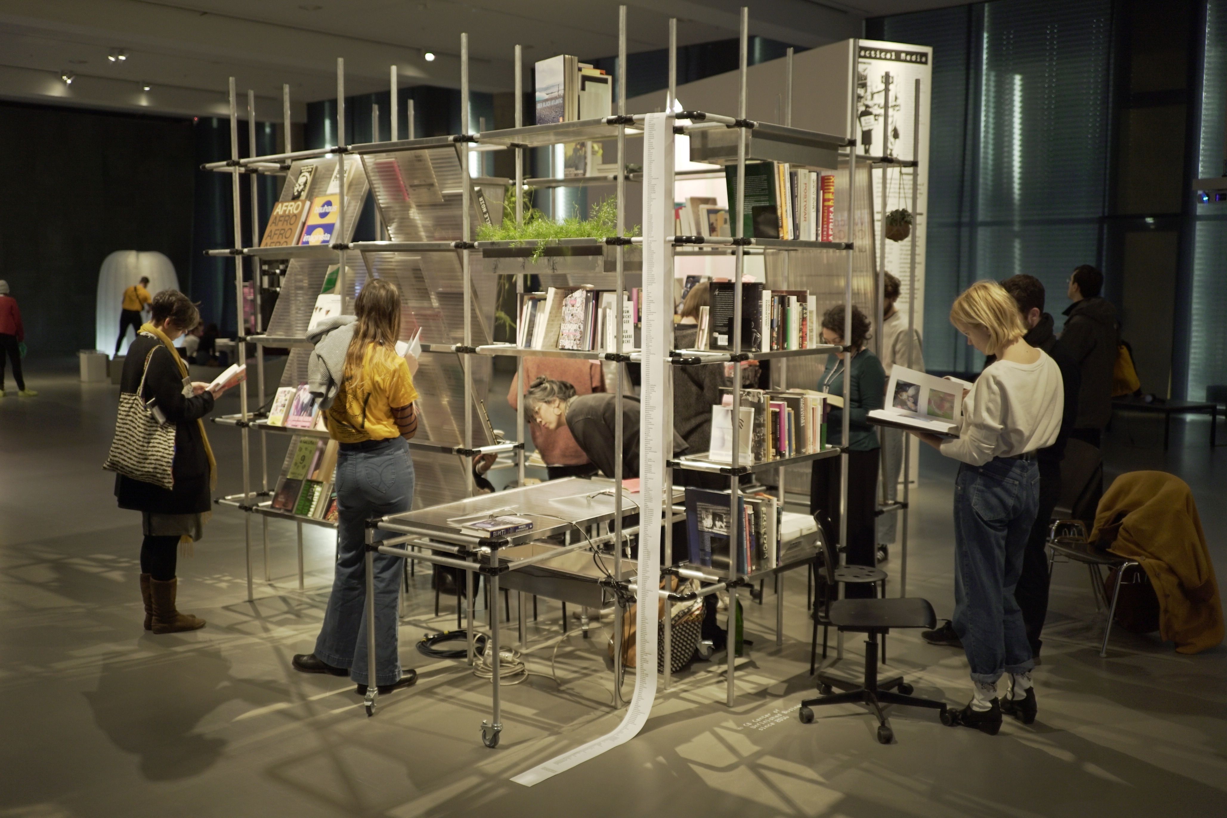 An innovative, multi-level book display with several people browsing its contents in a modern gallery.