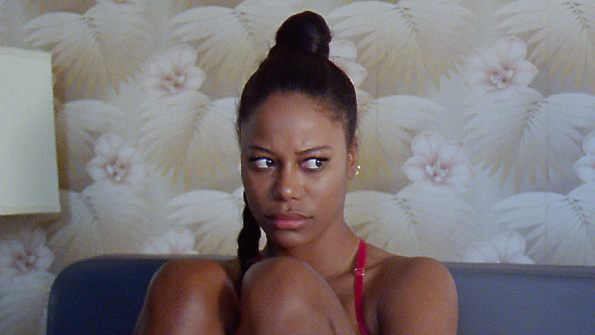 A young Black woman with her hair in a bun looks to the left with a worried expression.