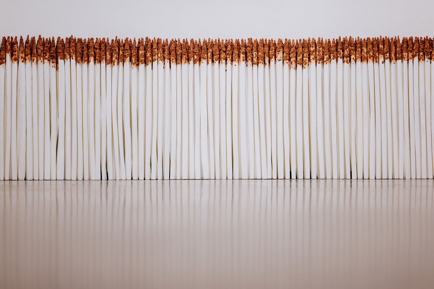Exhibition view: Cinthia Marcelle, Cerca Miragem (300 mourãos), 2005/2023, Robinia fence posts, lime paint, soil, variable dimensions, Courtesy the artist. Photo: Besim Mazhiqi