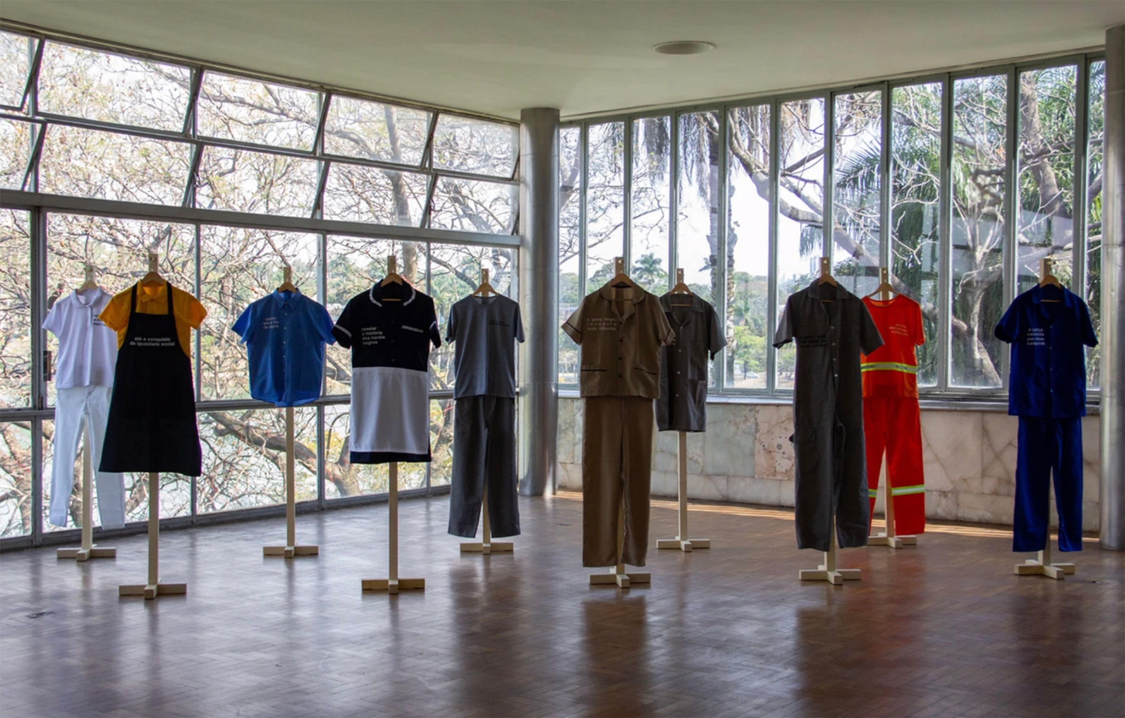 Diverse work uniforms displayed on stands in a bright room with large windows.