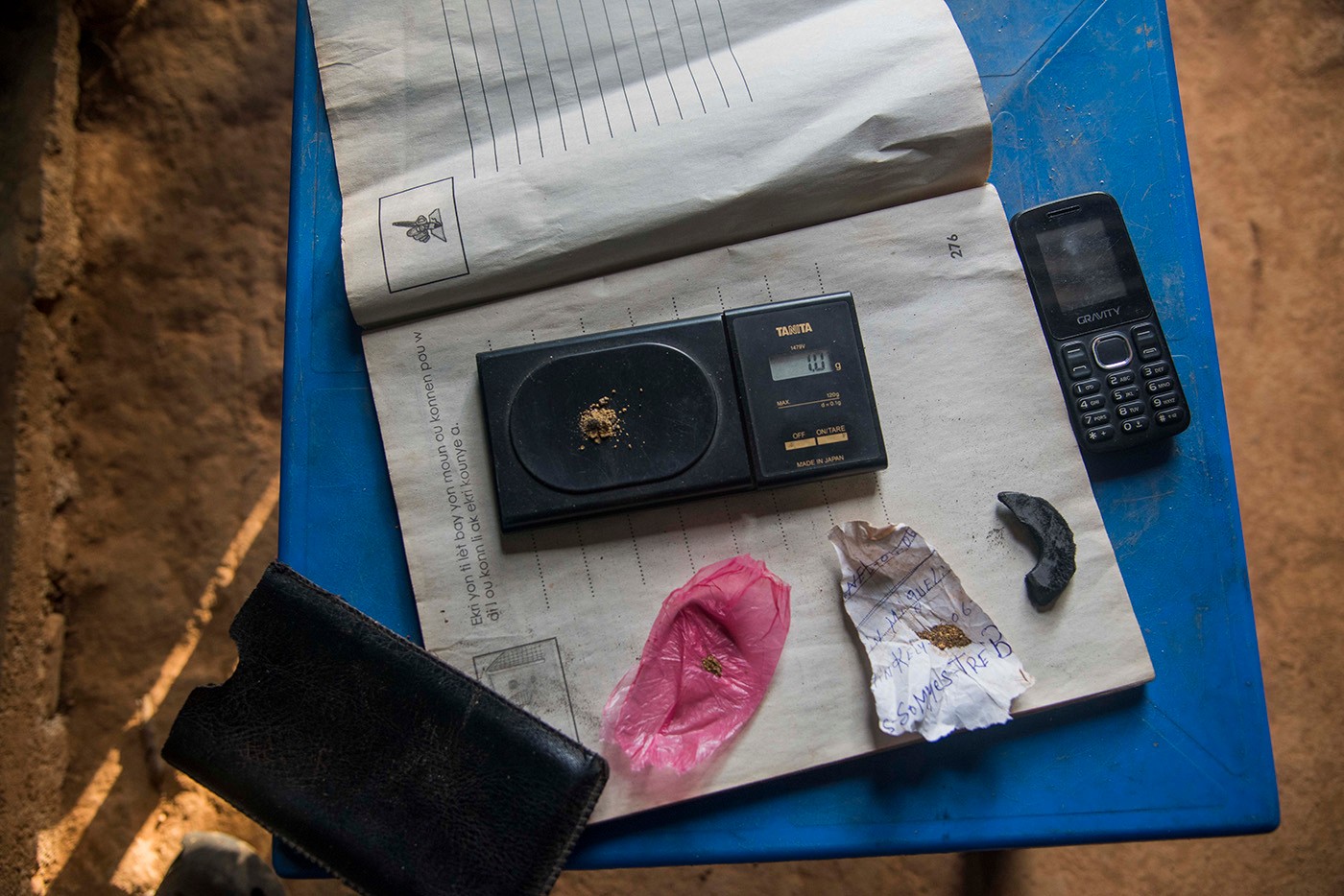 The work tools of a gold collector in Lakwèv, not far from the town of Mont-Organisé in the North-East department. On a small table are placed: a telephone, a magnet to extract the flakes from the gangue, some gold flakes and a scale. Photo: Jean Marc Hervé Abélard
