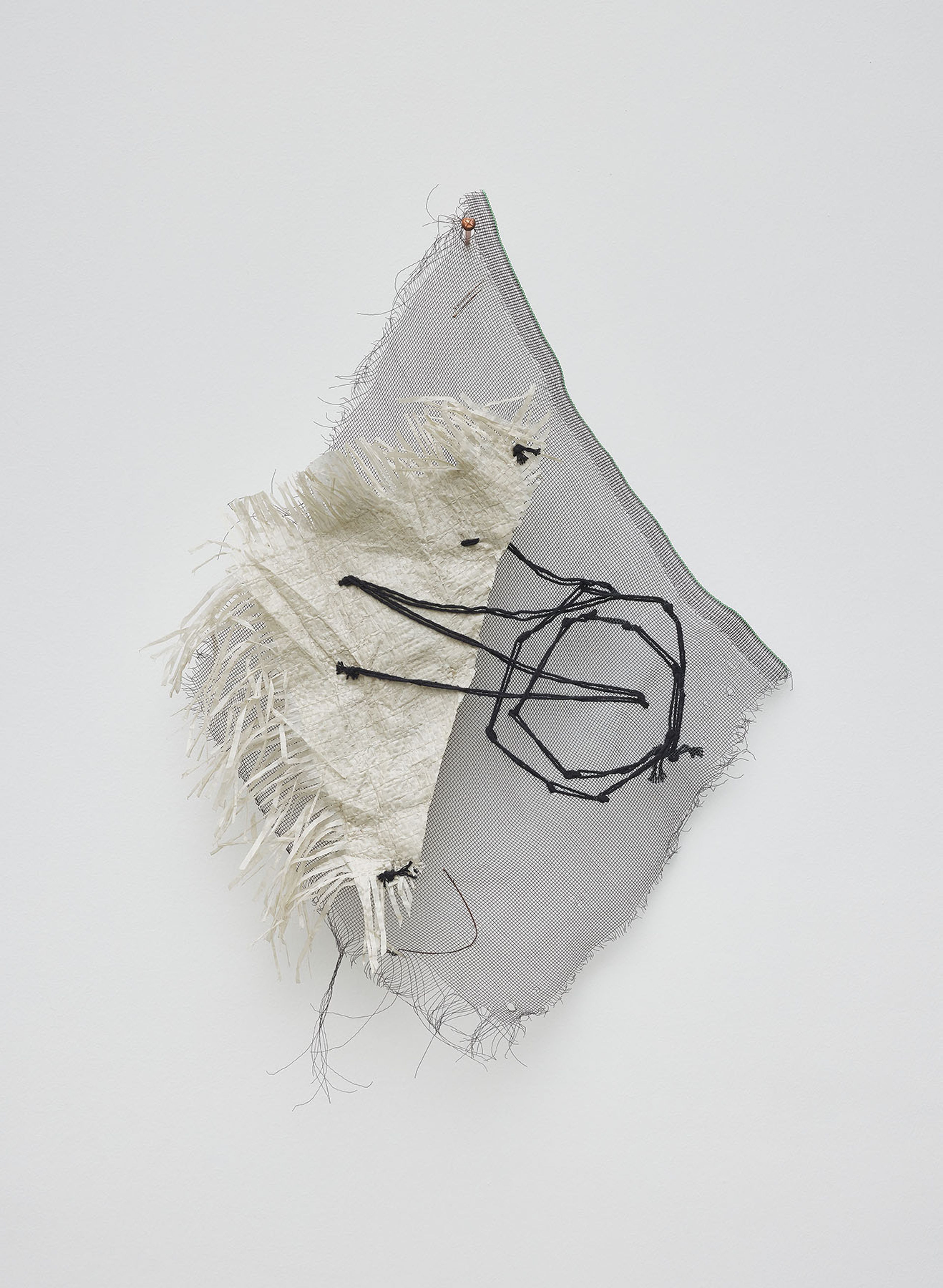 Abstract textile artwork made of layered grey mesh and frayed cream fabric, stitched with black thread, pinned to a white wall.