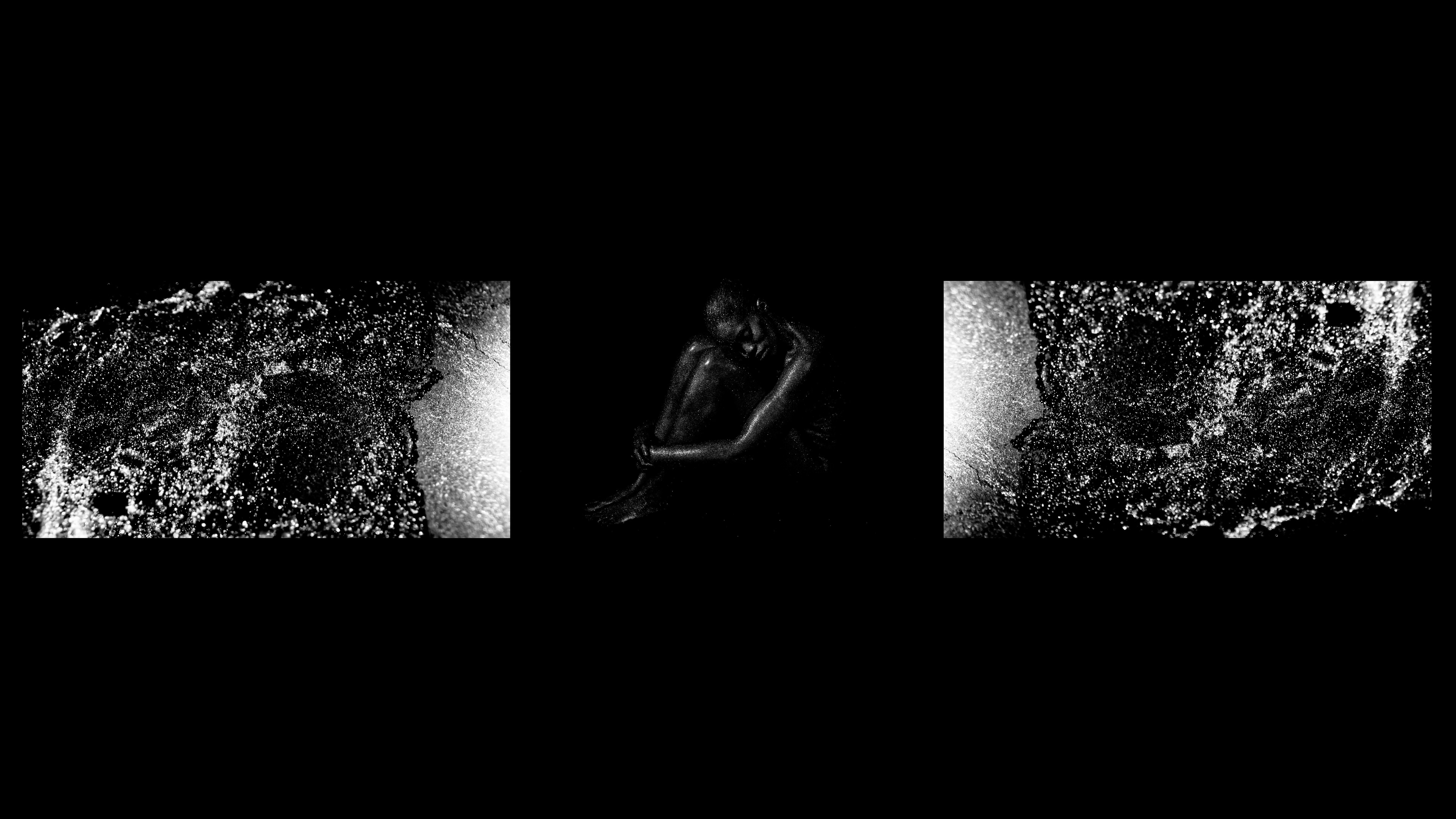 A monochromatic image of a dark, hunched figure seated in the center, flanked by two abstract, textured black and white panels.