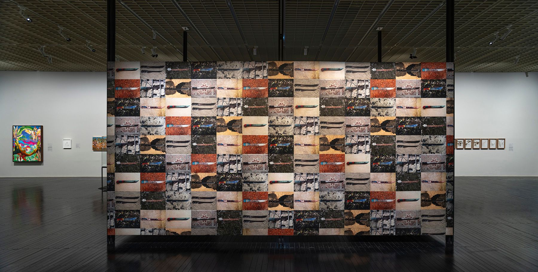 A large, freestanding art installation made of a grid of abstract, rectangular images stands in a museum gallery.