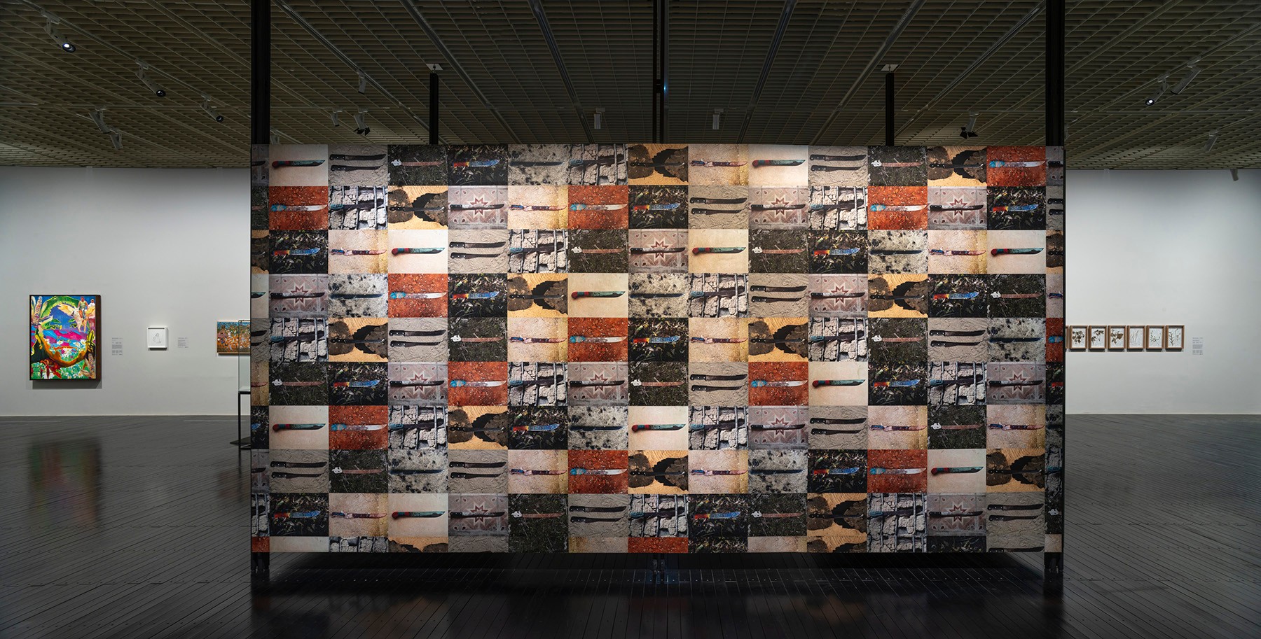 A large, freestanding art installation made of a grid of abstract, rectangular images stands in a museum gallery.