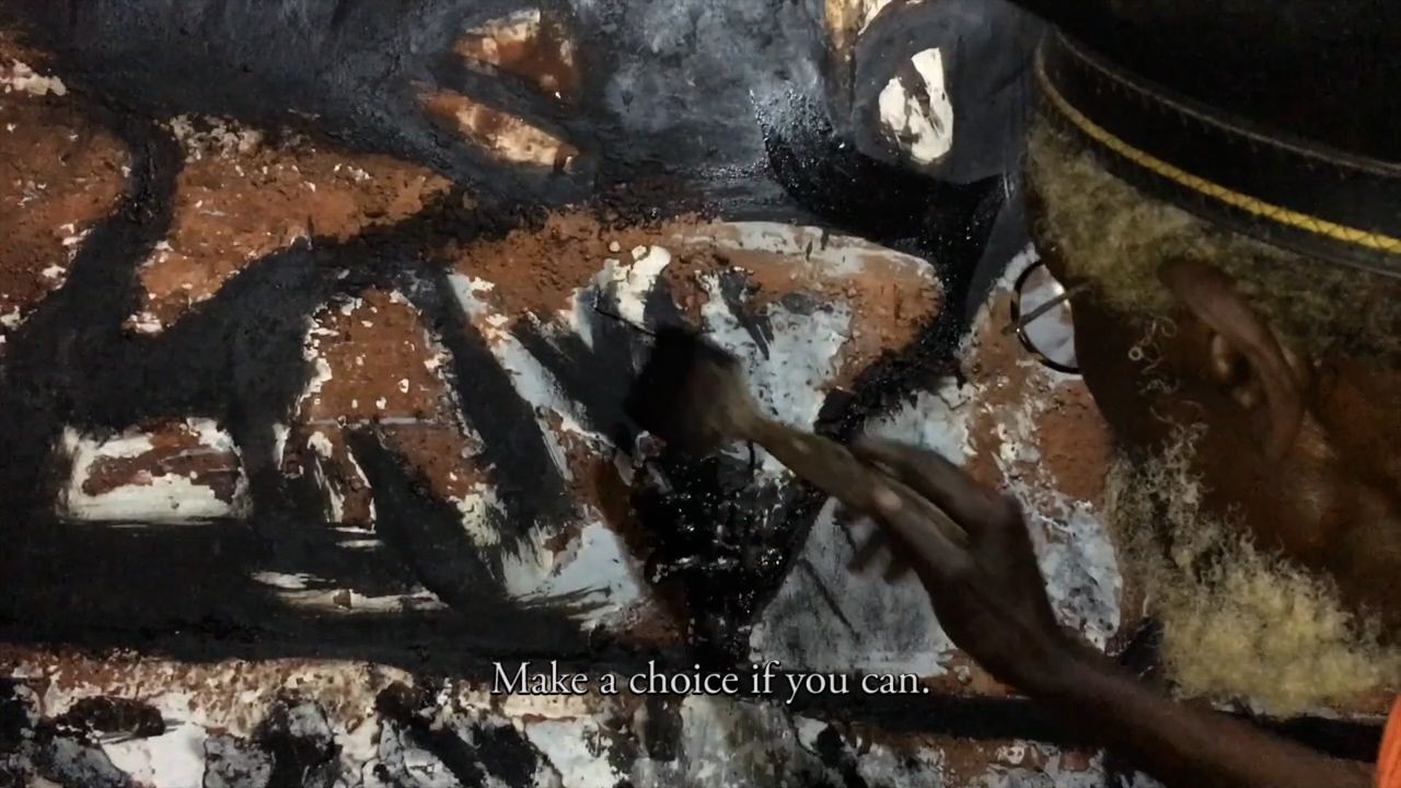 A person paints an abstract artwork in black, brown, and white, with the text "Make a choice if you can." at the bottom.
