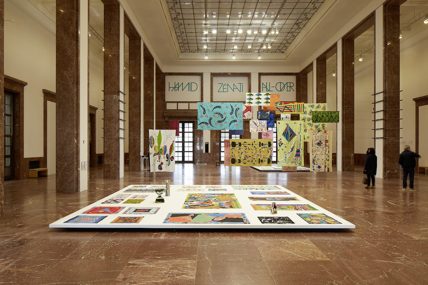 ”Hamid Zénati. All-Over”, installation view, Haus der Kunst, 2023. In line with the artist’s self-described “all-over” aesthetic principle, Hamid Zénati’s vibrant textile works fill the Mittelhalle of Haus der Kunst. Photo: Judith Buss
